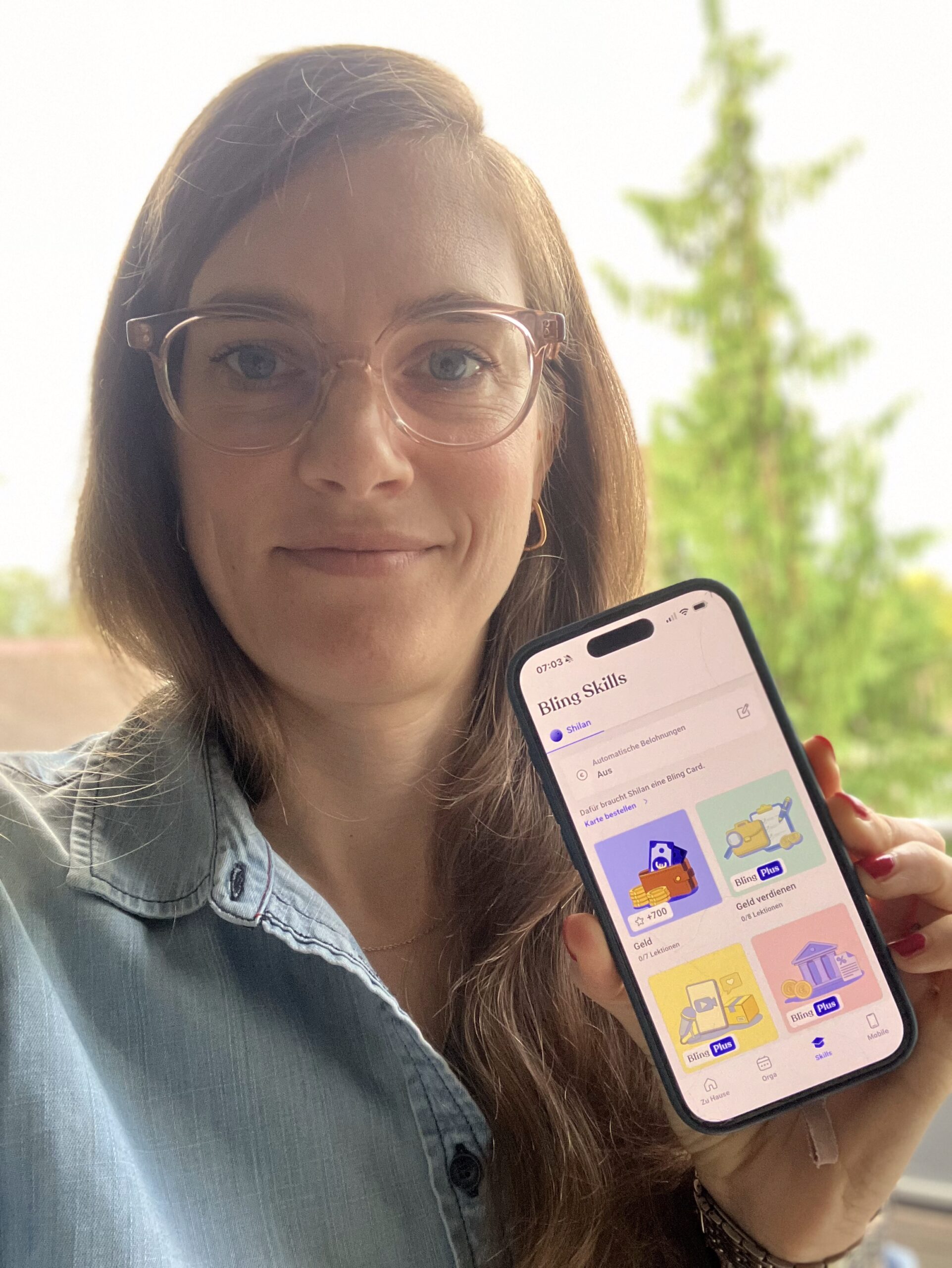 Linda Schliée zeigt die Bling! App auf einem Smartphone